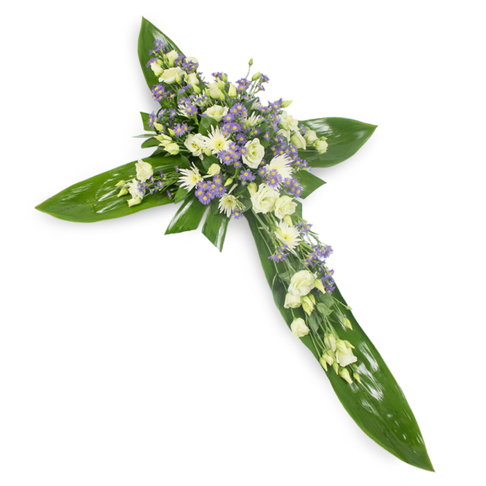 Bathed in soft, even light and photographed from a slight top-down viewpoint against a pure white surface, this floral cross is a quietly expressive composition that balances botanical strength and fragile beauty. The cross's underlying geometry is formed from broad, gleaming tropical leaves-Ti-leaf style greenery whose smooth planes and visible midribs create a rich, verdant frame that feels protective and enduring. Nestled within that green canvas, at the central junction and flowing outward along each arm, are clusters of pale lisianthus in shades of white and warm ivory; their layered, rose-like petals unfold with a genteel elegance and occasional closed buds suggest a stillness akin to prayer. Interspersed for contrast are small white chrysanthemum sprays whose compact, rounded blooms add sculpted texture, and delicate sprays of lavender-toned limonium or asters that introduce a soft, cooling hue and a starry intricacy. Slender sprigs of finer greenery are threaded through the blooms, lending air and a whisper of movement. The overall effect is meditative: the glossy foliage anchors the piece, the pale blooms evoke purity and solace, and the lavender accents hint at comfort and remembrance. This arrangement, with its careful craftsmanship and calming palette, is ideally suited to funerals, memorials or chapel displays in the West Ham area, perhaps chosen by families who appreciate understated beauty and regional care. It reads as a gentle, dignified offering of sympathy-crafted with floral experience and a respectful hand-meant to symbolize hope, faith and lasting memory.